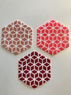 three hexagons made out of beading on a white surface with red and orange designs