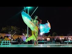 a woman is dancing on the dance floor in front of a group of people at night