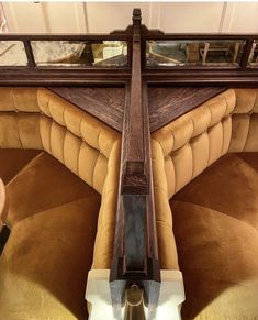 an upholstered couch with a wooden arm rests in front of a mirror