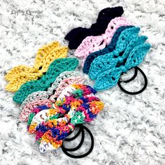 several crocheted hair ties laying on top of a white blanket with black handles