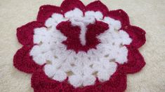 a crocheted red and white flower on the floor