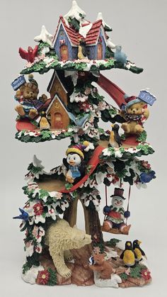 a christmas tree with bears and other animals on it's top, surrounded by snow