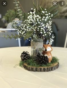 a vase filled with white flowers sitting on top of a wooden stump next to a pine cone