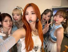 four girls with red hair are posing in front of a mirror and one girl is holding her hand up to the camera