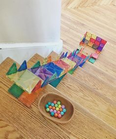 a wooden bowl filled with candy sitting on top of a hard wood floor next to colorful tiles