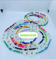 several bracelets with different colored beads and charms on white background, text reads kanndou beads