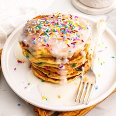 a stack of pancakes with frosting and sprinkles on a white plate