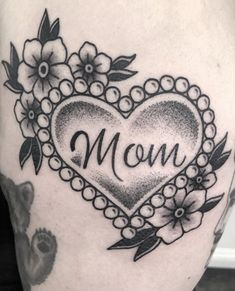 a woman's thigh with a heart and flowers on it that says mom in the center