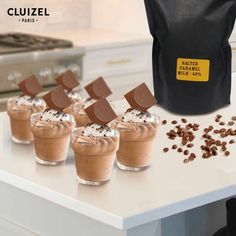 small cups filled with chocolate and marshmallows on top of a white counter