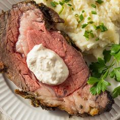 a plate with meat, mashed potatoes and green garnish on the side