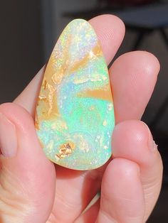 a person holding a piece of opal in their left hand with gold flecks on it