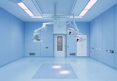 an empty hospital room with medical equipment hanging from the ceiling and lights on the walls