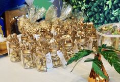 a table topped with lots of small glass jars filled with gold colored candies and candy