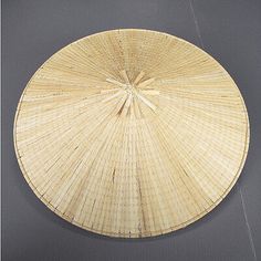 a large round bamboo basket hanging on the wall in front of a gray background with white trimmings