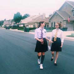 two girls in school uniforms walking down the street