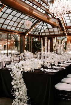 the tables are set with black linens, white flowers and crystal chandeliers