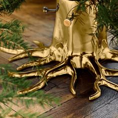 a gold octopus christmas tree ornament on a wooden floor with pine needles and branches