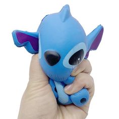 a hand holding a small blue toy with big eyes and horns on it's head