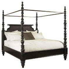 a four post bed with white sheets and pillows on it's headboard is shown