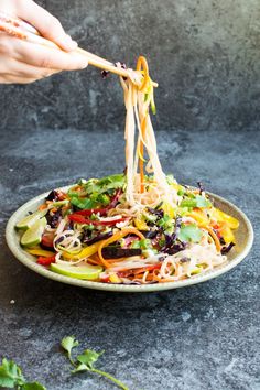 someone is holding chopsticks over a salad in a bowl