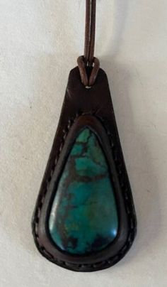 "Leather Necklace with Semi Precious Chrysocolla Cabochon. The leather is cut and wet molded over the cabochon. The two layers of leather are handstitched together and the edges are dyed and waxed.  The rolled leather cord is 20\" long with a stainless steel clasp.  This pendant measures 2 7/8\" tall and 1 1/2\" wide. Handmade in California" Artisan Leather Necklace For Everyday, Vintage Leather Jewelry With Strap, Artisan Jewelry With Leather Strap For Gift, Vintage Leather Jewelry With Patina, Artisan Hand Tooled Jewelry, Brown Leather Jewelry With Patina, Green Leather Jewelry Gift, Green Leather Jewelry For Gifts, Green Leather Jewelry As A Gift