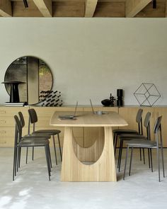 a dining room table with chairs and a circular mirror on the wall in front of it