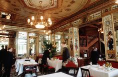 people are sitting at tables in an ornately decorated restaurant