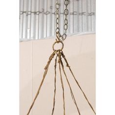 a metal object hanging from a chain on top of a white wall in a room