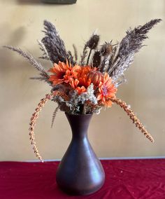 a vase filled with lots of flowers on top of a red cloth covered tablecloth