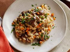 a white plate topped with meat and vegetables next to a fork on top of a wooden table