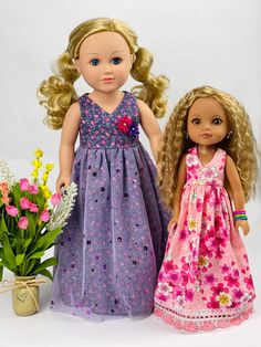 two dolls standing next to each other in front of flowers