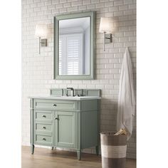 a bathroom with a green vanity and white brick wall behind it, along with a large mirror above the sink