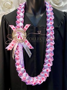 a graduation gown with pink ribbon and badge on it