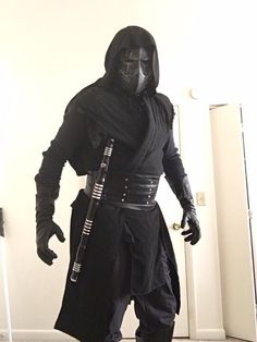 a man dressed in darth vader costume and holding a cane standing next to a door