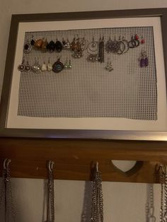 there are many different necklaces hanging on the wall in front of a framed picture