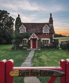 a red house with a sign that says burnt farm cottage on it's front gate