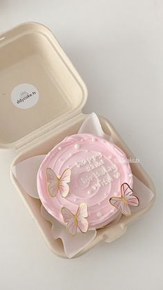 a pink cake in a box with butterflies on it and the words happy birthday written on top