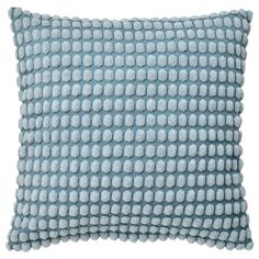 a light blue pillow with white dots on the front and back, sitting on a white surface