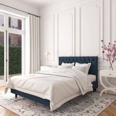 a bedroom with white walls and wood flooring has a blue upholstered bed