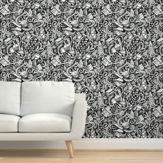 a white couch sitting in front of a wall with black and white designs on it