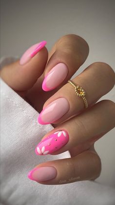 a woman's hand with pink and white manies on it, holding a gold ring