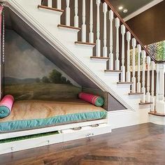 a dog bed under the stairs in front of a stair case with a painting on it