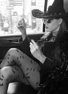 a woman sitting in the back seat of a car wearing a witches hat and stockings