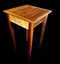 a small wooden table with one drawer on the top and two legs at the bottom