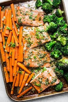 salmon, broccoli and carrots in a baking pan with seasoning sprinkled on top