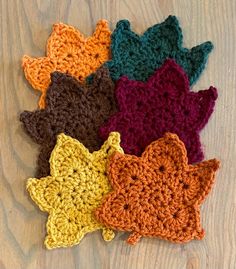 six crocheted stars are arranged on a wooden surface, each with different colors