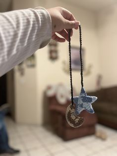 a person holding a blue and white star ornament in their hand with a black string