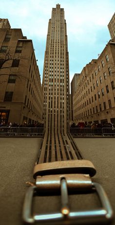 a belt that is laying on the ground in front of some tall buildings and people