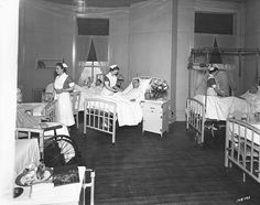 an old black and white photo of nurses in a hospital bed room with their babies