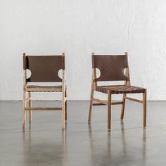 two chairs sitting side by side in front of a white wall and concrete flooring